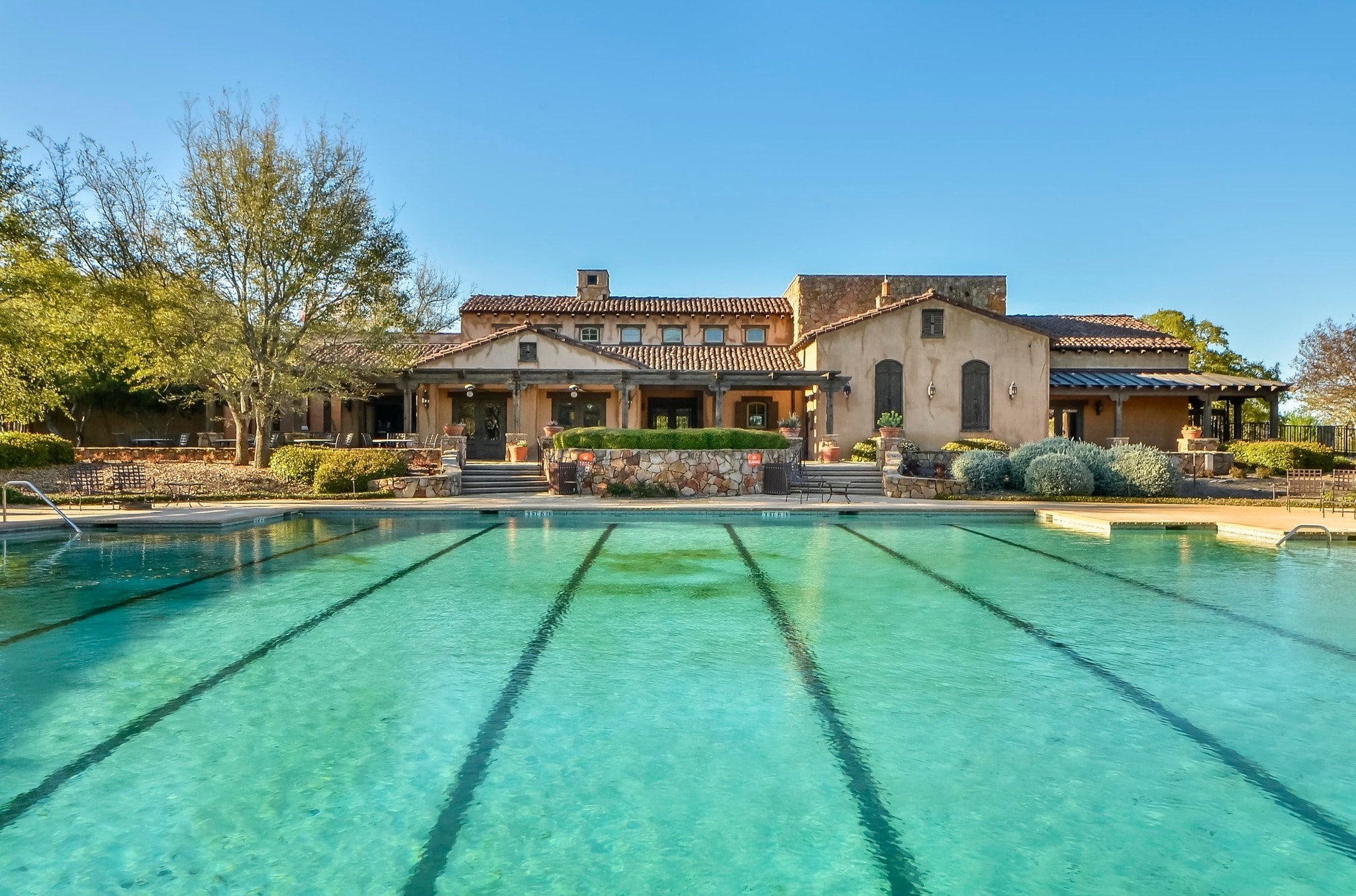 Cimarron Hills lap pool with full Mediterranean clubhouse facade and stone steps