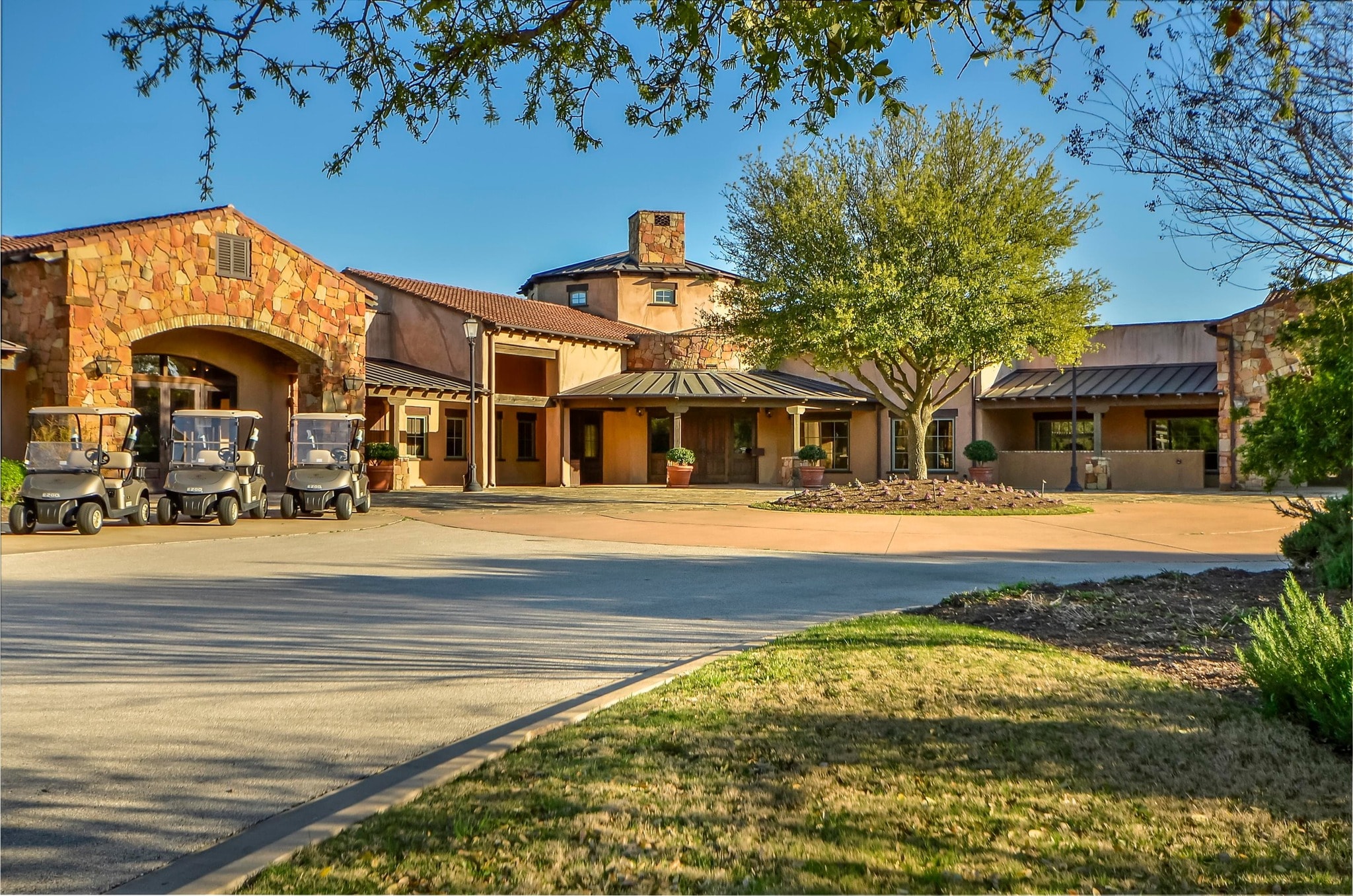 Cimarron Hills clubhouse motor court with golf carts and stone arch entry
