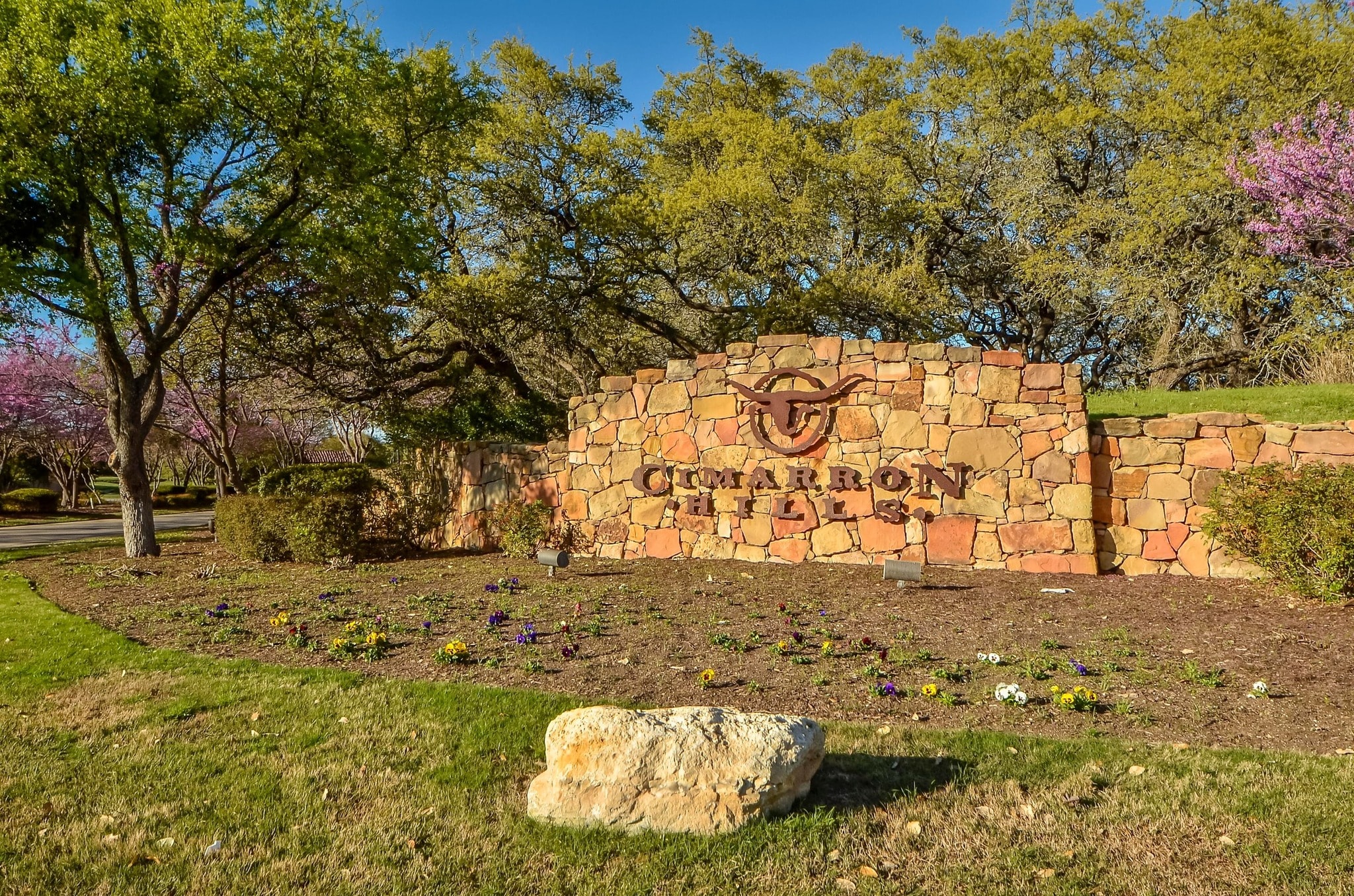 Cimarron Hills stone entry monument sign with longhorn logo and spring blooms