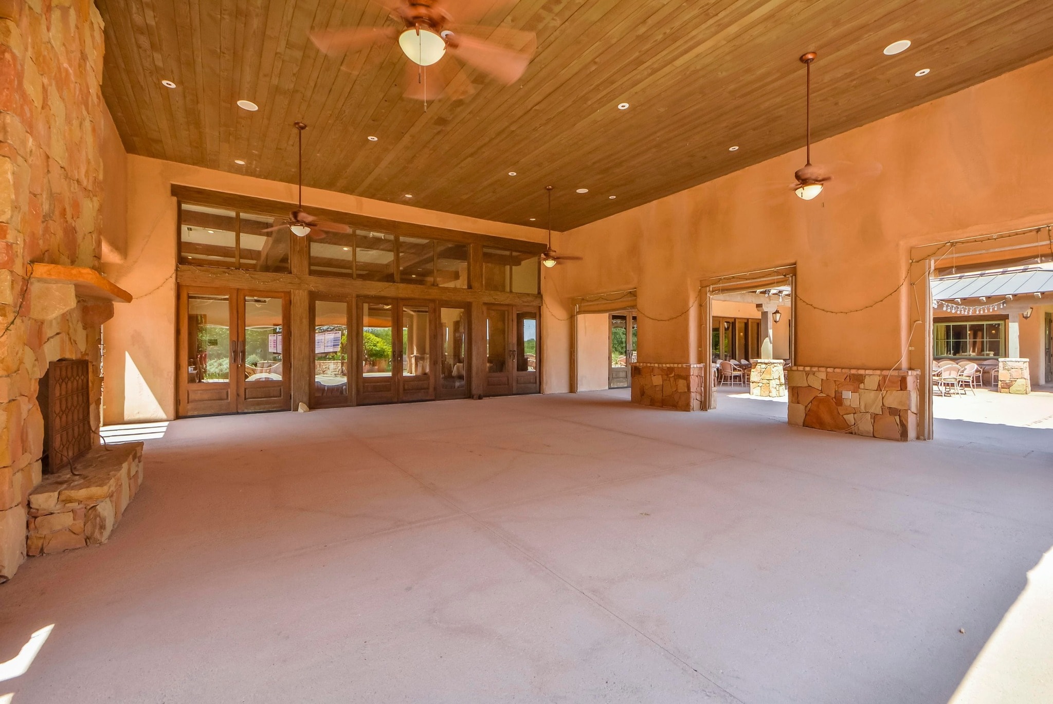 Club event pavilion with wood ceiling, ceiling fans, and stone fireplace